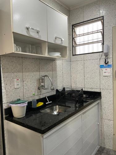 a kitchen with a sink and a black counter top at Linda Kitnet mobiliada in São Vicente