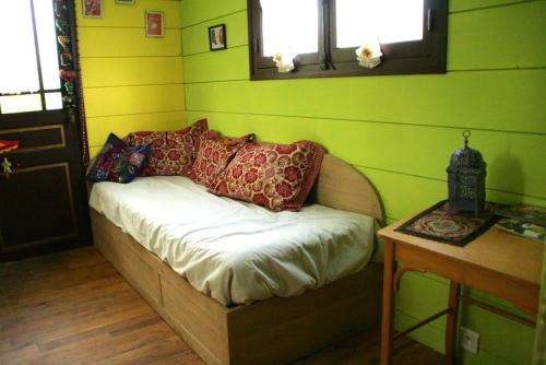 a small bed in a room with green walls at Roulotte de cirque à Rocamadour in Rocamadour
