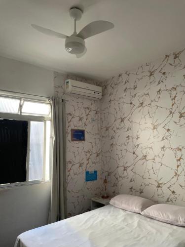 a bedroom with a bed and a ceiling fan at Linda Kitnet mobiliada in São Vicente