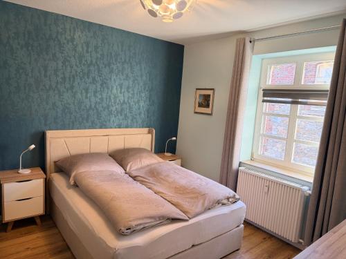 a bed in a bedroom with a blue wall at Altstadtnest - gemütliche Wohnung nahe der Burg in Donnerberg