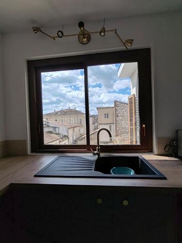 a kitchen with a sink and a large window at Les toits du Lot in Villeneuve-sur-Lot
