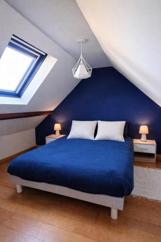 a bedroom with a blue bed in a attic at Les Champs d'Opale in Bréxent-Énocq