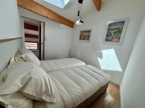 a white bedroom with a bed and a window at L'Écrin Rustique in Couzeix