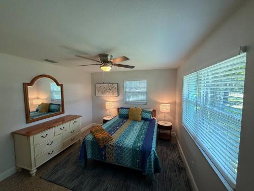 a bedroom with a bed and a mirror and a window at 1008 Gardens in Vero Beach