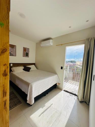 a bedroom with a bed and a sliding glass door at Flat Dourado a 5minutos do Parnaíba Shopping in Parnaíba