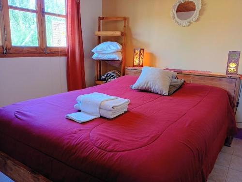 a bedroom with a red bed with towels on it at Cabañas Rowal Malbec Potrerillos in Potrerillos