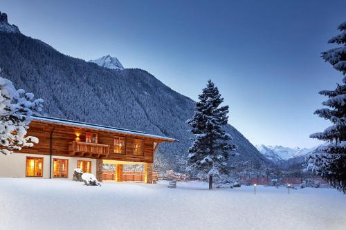 a log cabin in the snow with a tree at Relais&Châteaux Spa-Hotel Jagdhof in Neustift im Stubaital