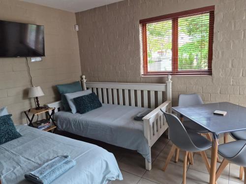 a bedroom with two beds and a table and a table and chairs at 5Viooltjie in Riversdale