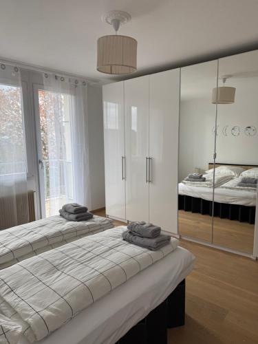a white bedroom with two beds and a mirror at Ferienhaus Alpenblick in Steinen