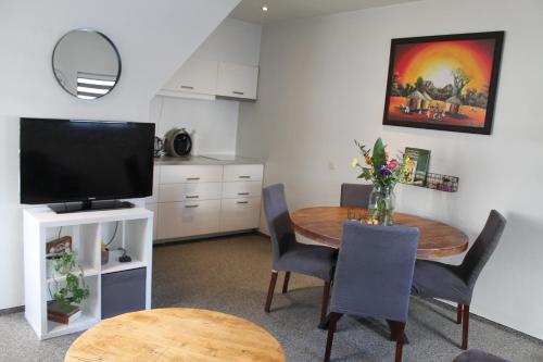 a kitchen and dining room with a table and a television at Geuldal Guest Apartments in Valkenburg