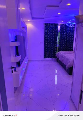 a purple room with a tv and a couch at Ngalle guest house in Buea