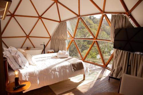 a bedroom in a yurt with a bed and a large window at Refúgio Kuri'y Campos do Jordão in Campos do Jordão