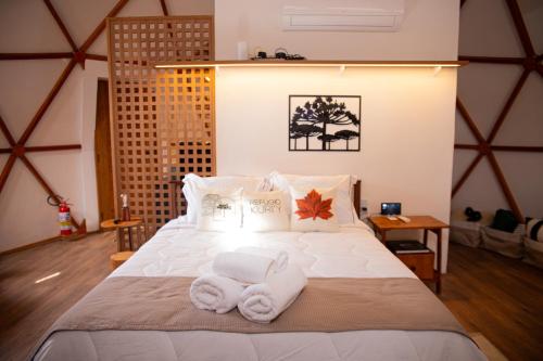 a bedroom with a bed with towels on it at Refúgio Kuri'y Campos do Jordão in Campos do Jordão