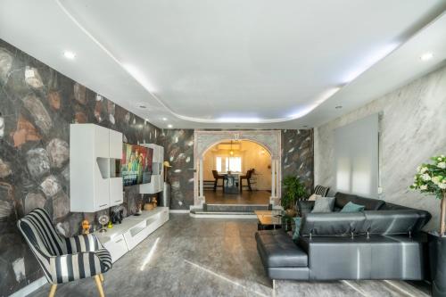 a living room with a black leather couch and chairs at Villa Jazmín - Piscina - BBQ - Jardín - Chill out in Masía Aldamar