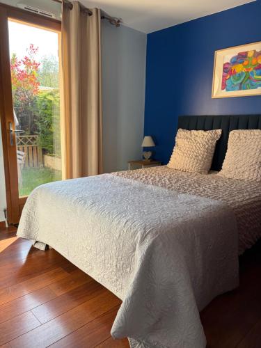 a bedroom with a bed with a blue wall and a window at Appartement Cambita in Montévrain