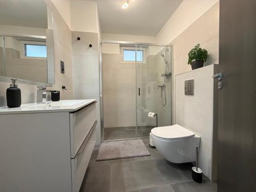 a white bathroom with a shower and a toilet at Minimál Éden in Balatonlelle