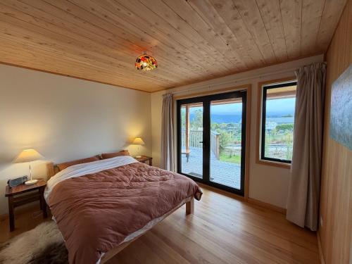 a bedroom with a bed and a large window at Whare Aorere in Collingwood