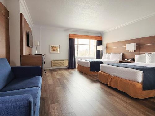 a hotel room with two beds and a couch at Hotel L'Oie des neiges in Lévis