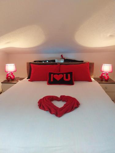 a red heart pillow on a bed with two lamps at Park Apartment in Kočani