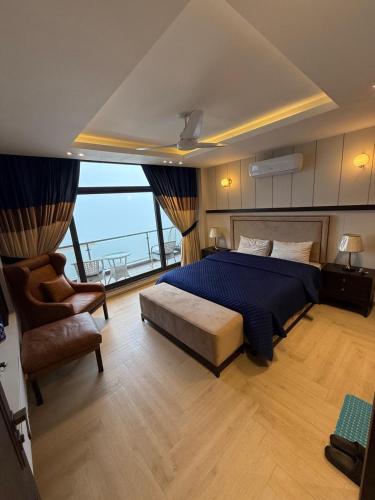a bedroom with a bed and a chair and a window at Premium Murree Apartment With Stunning Views in Murree