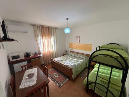 a small room with a bed and a desk and a table at La Perla del Dolcedorme in San Lorenzo Bellizzi