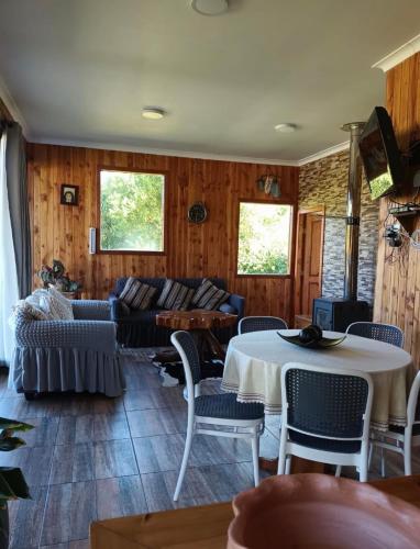 a living room with a couch and a table and chairs at Cabaña la nonita, queule in Queule