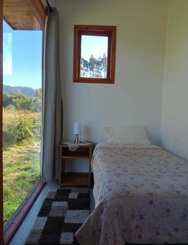a bedroom with a bed and a window at Cabaña la nonita, queule in Queule