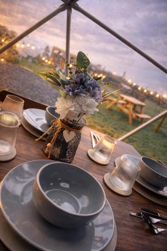 a wooden table with plates and a vase of flowers at Alpaca Hideaway in Llanstadwell