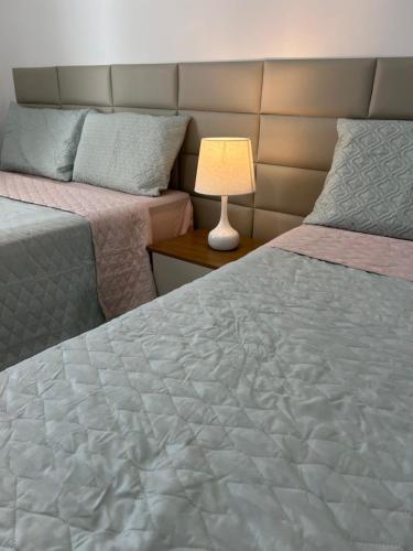 ein Schlafzimmer mit zwei Betten und einer Lampe in der Unterkunft Flat Granito e Jasmim in Conde
