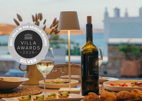a bottle of wine sitting on a table with food at Coocono Tinos Private Boutique Villas in Tinos