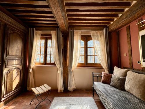 a living room with a couch and two windows at Le 16 authentique au cœur de la ville in Lisieux