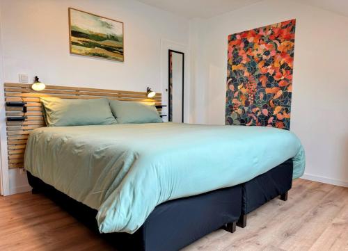 ein Schlafzimmer mit einem großen Bett und einem Gemälde an der Wand in der Unterkunft Le BrasÔvert in Bras