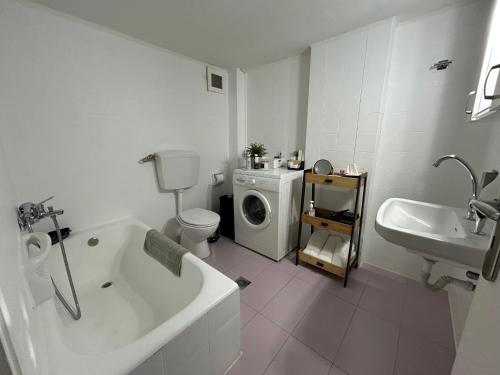 a bathroom with a tub and a sink and a washing machine at MG elounda apt in Elounda