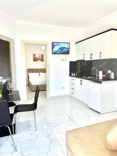 a white kitchen with a table and a dining room at Taku Rooms Vlora in Vlorë