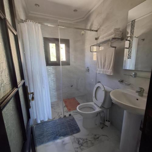 a white bathroom with a toilet and a sink at Mina House in Chefchaouen