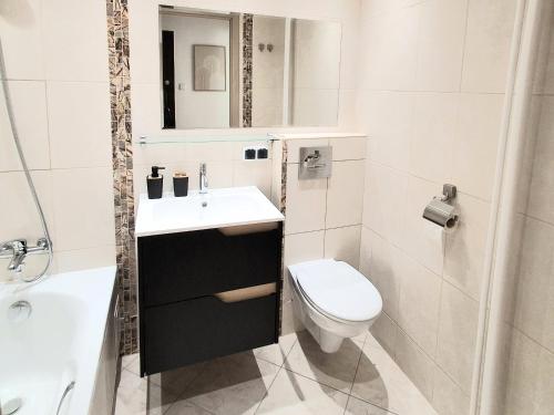 a white bathroom with a sink and a toilet at Apartament Bursztynowy in Ustka