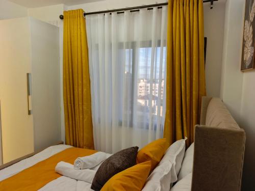 ein Schlafzimmer mit einem Bett und einem Fenster mit gelben Vorhängen in der Unterkunft yNest Studio in Syokimau