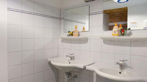 a white tiled bathroom with two sinks and a mirror at Sahara wild camping in Mhamid