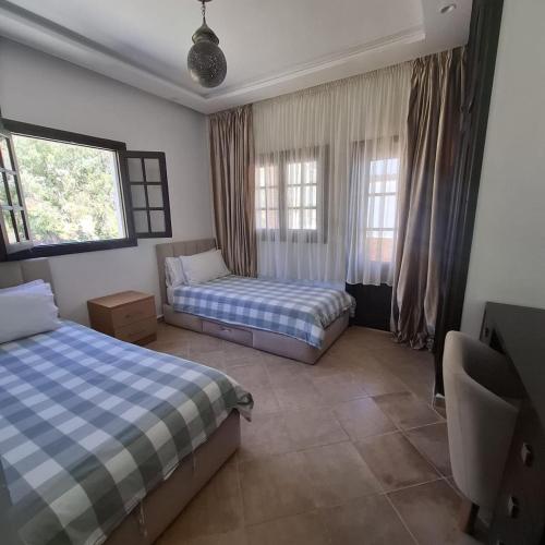 a bedroom with two beds and two windows at Mina House in Chefchaouen