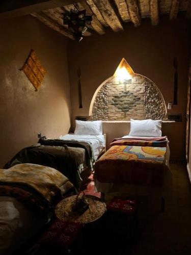 a room with two beds and a stone wall at Sahara wild camping in Mhamid