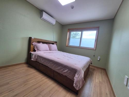 a bedroom with a bed with pink sheets and a window at 비우리게스트하우스 in Kujŏm