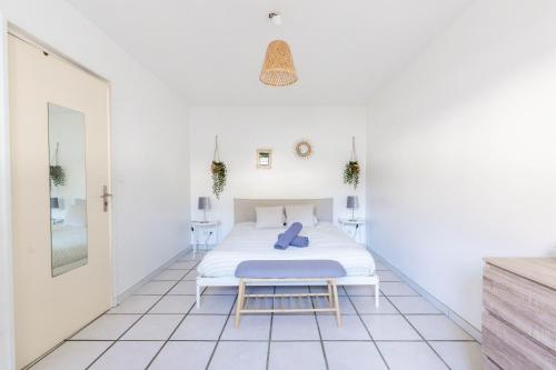 a white bedroom with a bed and a table at T2 cocooning proche Paris et Disney in Lagny