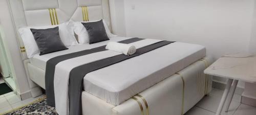 a large white bed with black and white sheets and pillows at Blossom Homes A2 in Mombasa