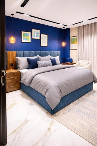 ein Schlafzimmer mit einem großen Bett und einer blauen Wand in der Unterkunft LMY Murree Boutique Apartments - Expressway Near Coffee Bean in Lower Topa