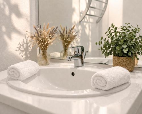 a white bathroom sink with two towels on it at L Echappee Jardin prive proche plage Sainte Cecile in Camiers