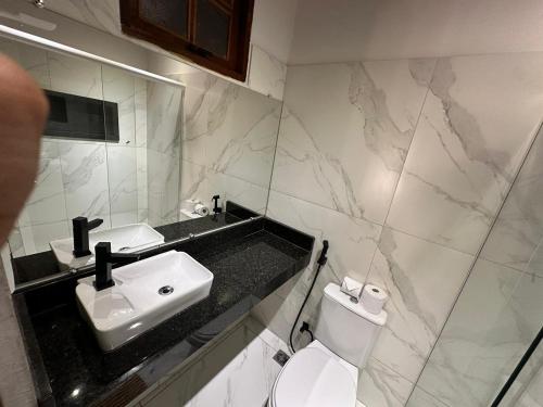 a white bathroom with a sink and a toilet at Pousada Acquarela Paraty -a 450 mts do centro historico! we also speak English in Paraty