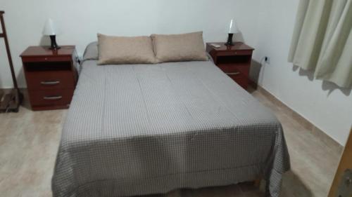 a bedroom with a bed with two nightstands and two lamps at Depto in Navarro