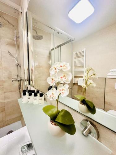 a bathroom with a sink with flowers in vases on it at Le Petit - Ihre Pension in Essen in Essen
