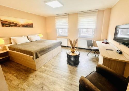 a bedroom with a bed and a desk and a tv at Le Petit - Ihre Pension in Essen in Essen