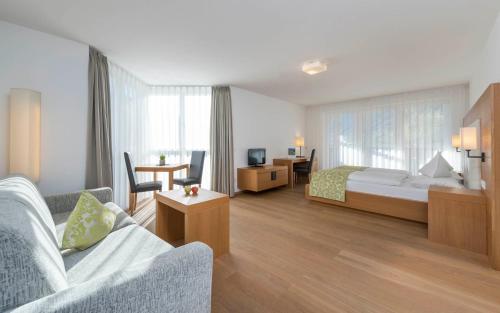 ein Hotelzimmer mit einem Bett und einem Wohnzimmer in der Unterkunft Vinschgerhof in Schlanders